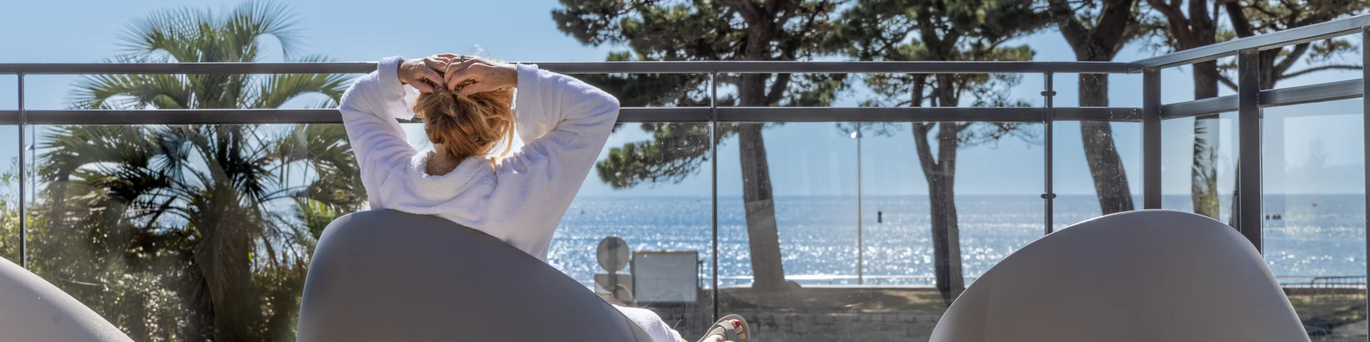 A woman lounging in front of the sea in the Relais Thalasso herbal tea area
