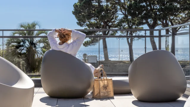 Une femme se prélassant face à la mer dans l'espace Tisanerie du Relais Thalasso