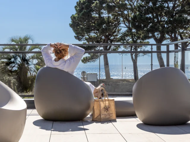A woman lounging in front of the sea in the Relais Thalasso herbal tea area