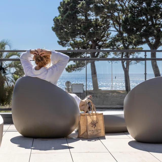 Une femme se prélassant face à la mer dans l'espace Tisanerie du Relais Thalasso