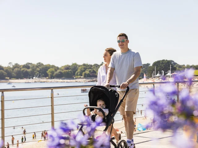 Couple with pushchair on a walk along Plage du Trez
