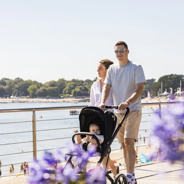 Couple with pushchair on a walk along Plage du Trez