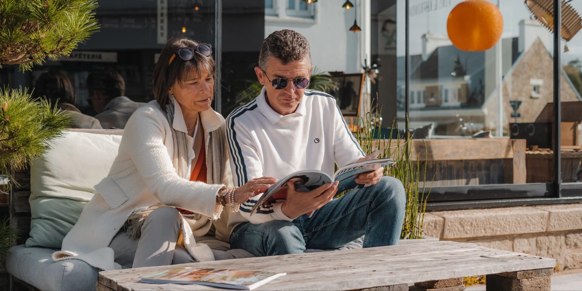 Couple consultant un magazine sur la terrasse du Bateau Libre Hôtel - Bar à vin & Cocktail