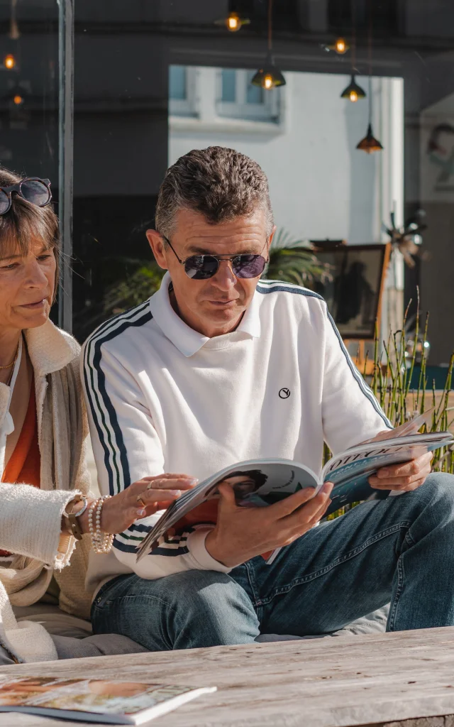 Couple consultant un magazine sur la terrasse du Bateau Libre Hôtel - Bar à vin & Cocktail