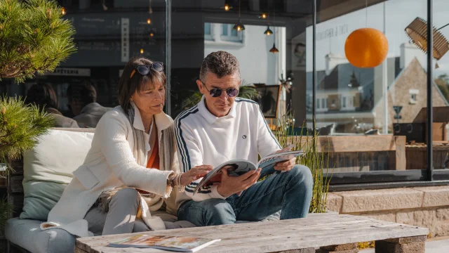 Couple consultant un magazine sur la terrasse du Bateau Libre Hôtel - Bar à vin & Cocktail