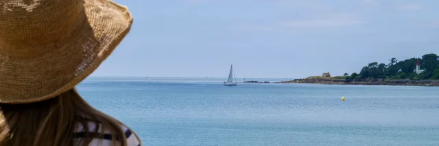 Jonge vrouw bewondert de Pointe de Combrit vanaf het Plage du Trez in Bénodet
