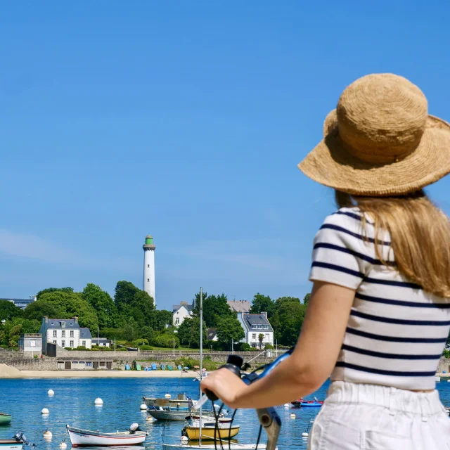 Junge Frau auf dem Fahrrad bewundert Bénodet von Sainte-Marine aus