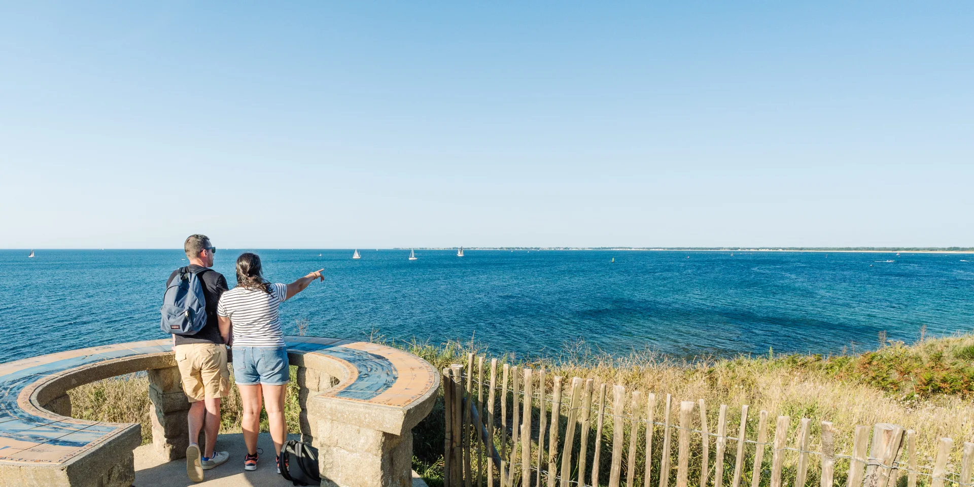 Couple admiring the horizon at the Pointe de Groasguen orientation table in Bénodet