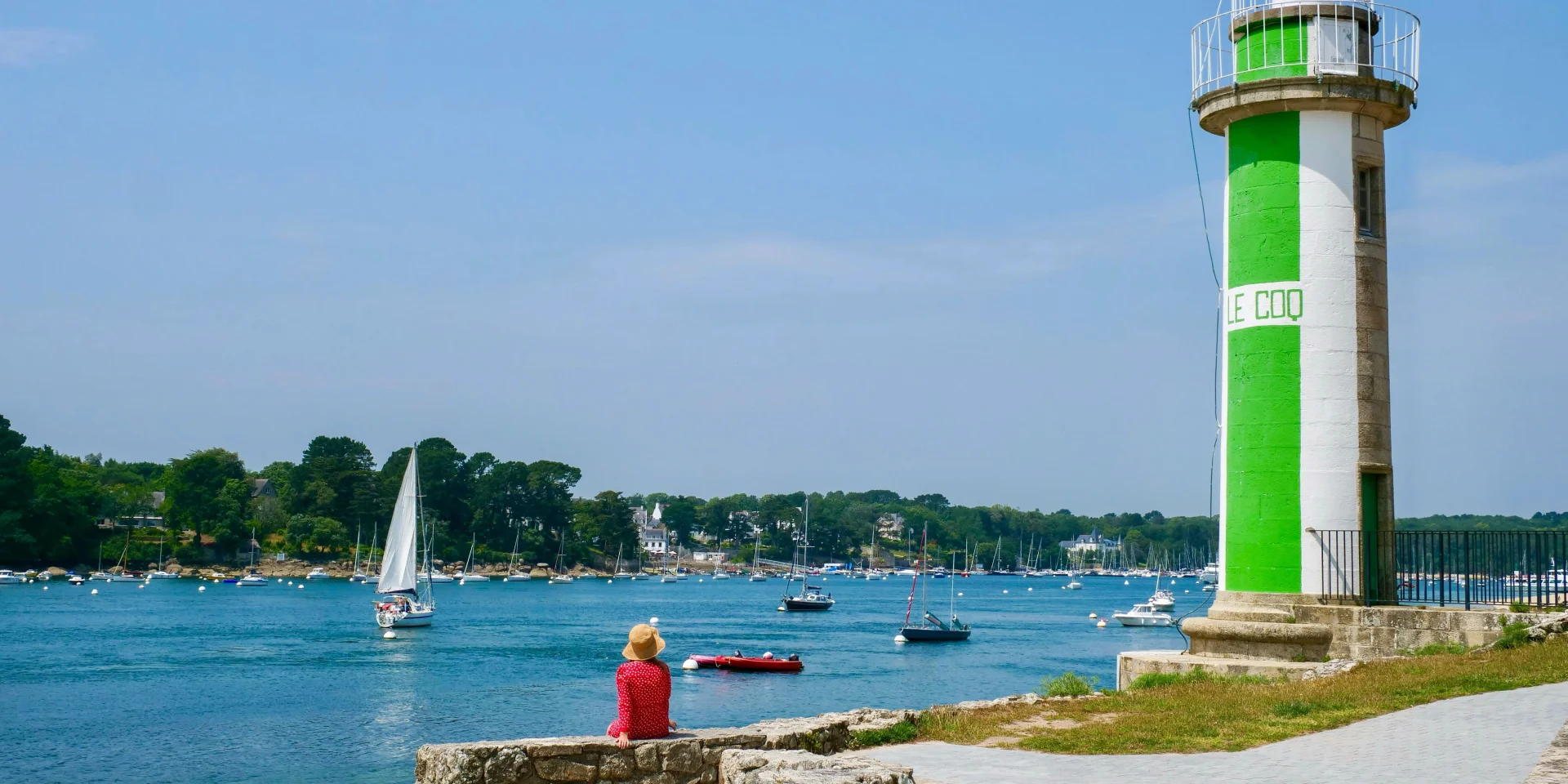 Young woman seated near the Coq lighthouse in Bénodet