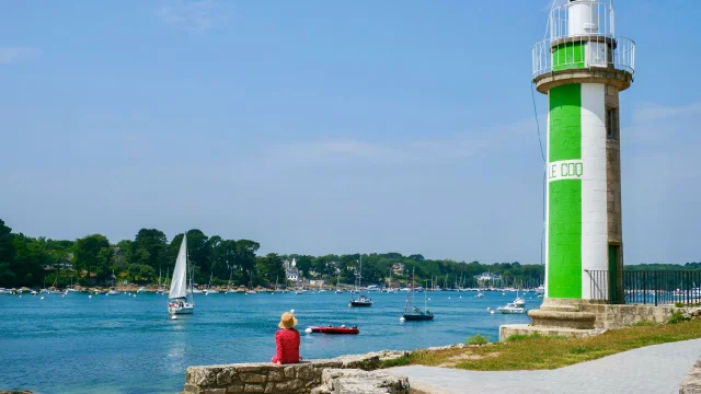 Jeune femme assise près du Phare du Coq à Bénodet