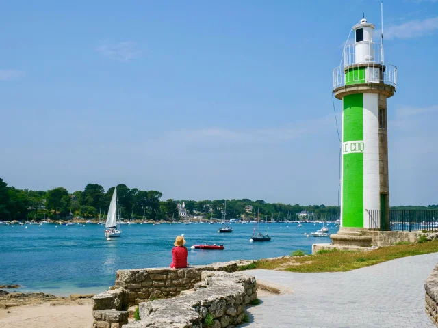 Jeune femme assise près du Phare du Coq à Bénodet