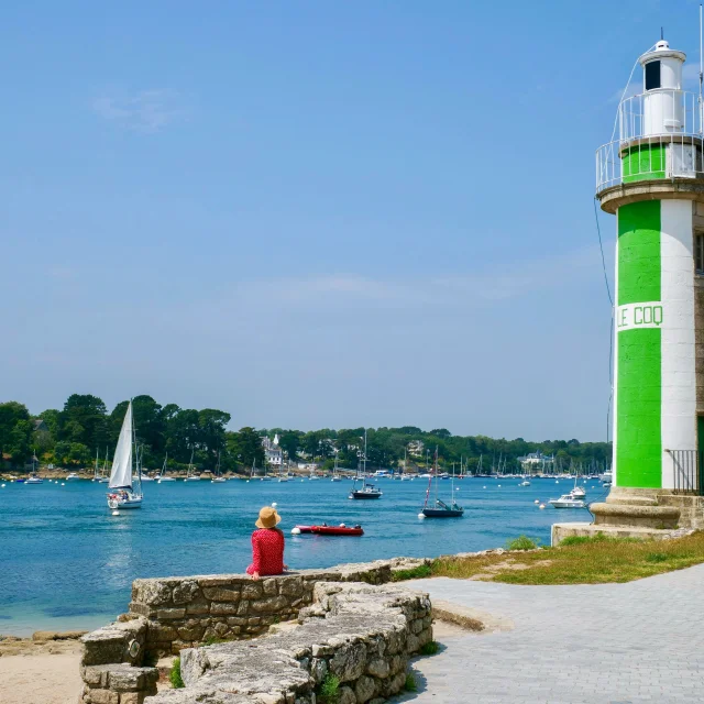 Young woman seated near the Coq lighthouse in Bénodet