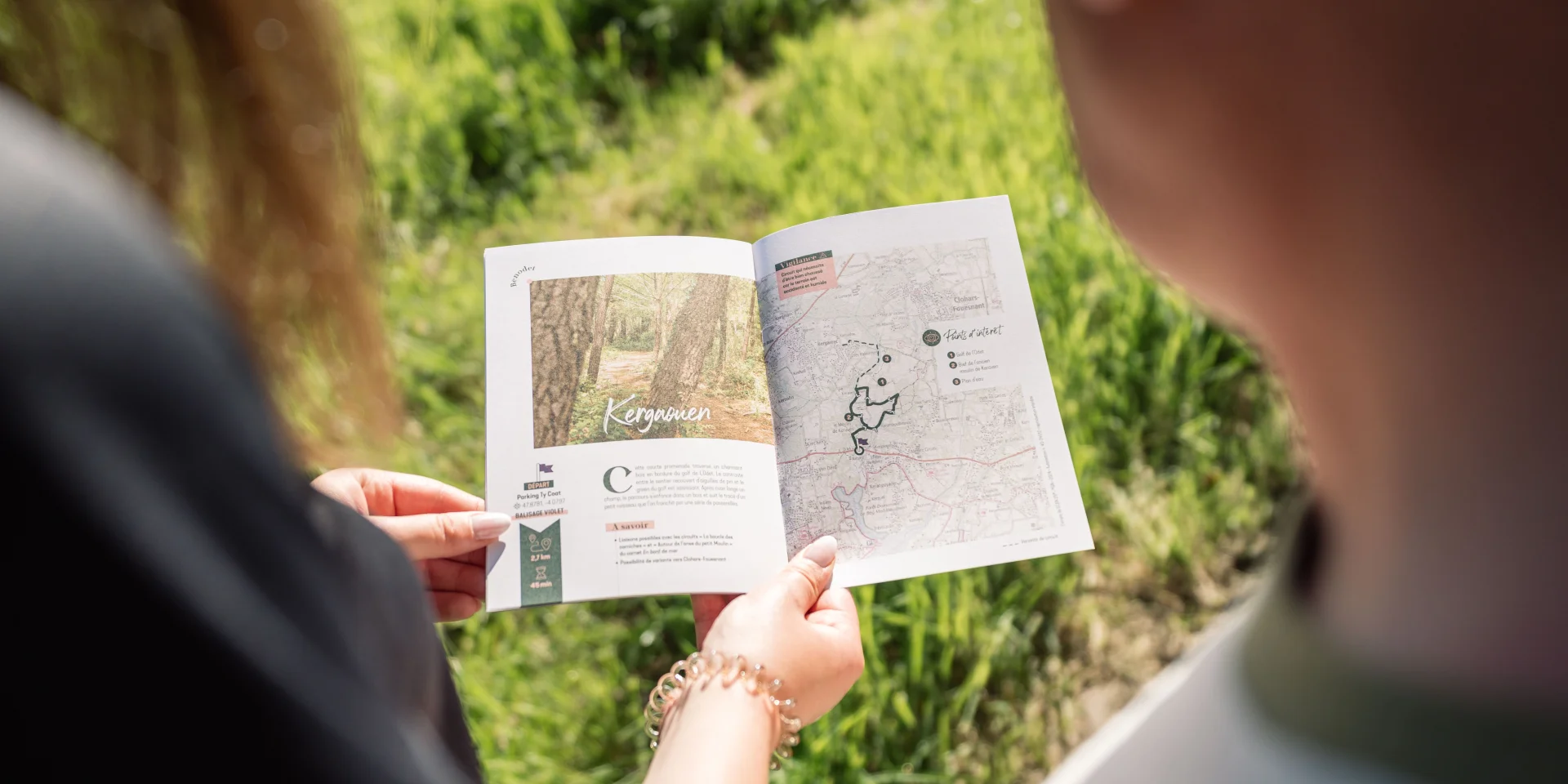 Zwei Spaziergänger betrachten das Carnet du Promeneur auf der Seite über den Spaziergang im Bois de Kergaouen in Bénodet.
