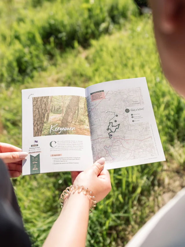 Deux promeneurs regardant la Carnet du Promeneur à la page concernant la balade dans le Bois de Kergaouen à Bénodet
