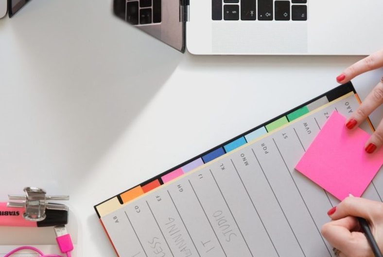 Une partie d'un clavier d'ordinateur et une main qui écrit sur un agenda